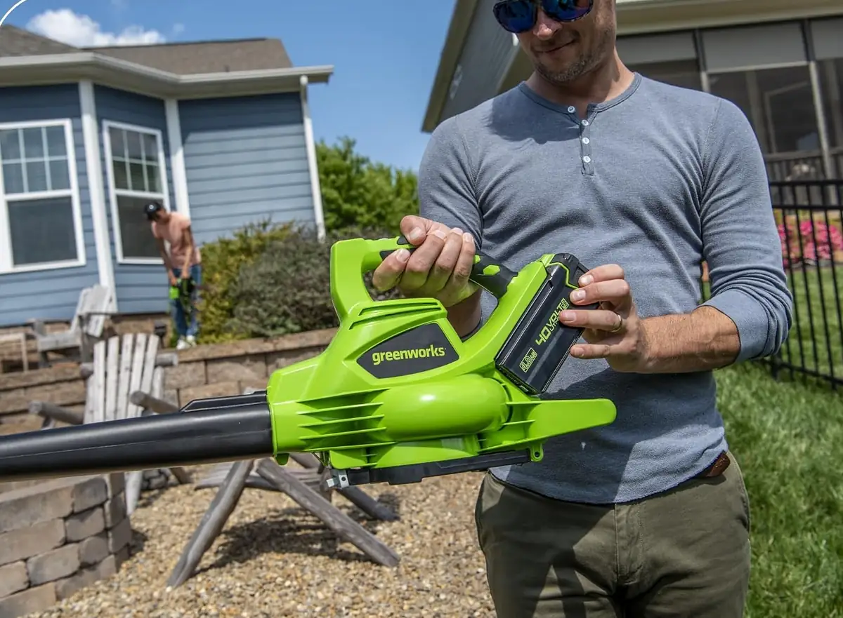 Man in a backyard holding the Greenworks 40V cordless blower vacuum with the battery installed