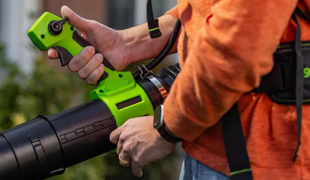 Hand on the green variable speed trigger and turbo switch of the Greenworks 80V backpack blower