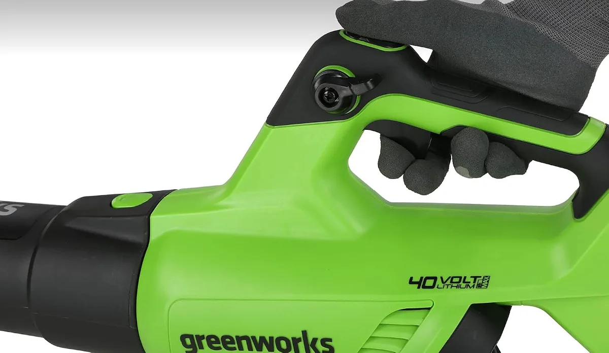 Gloved hand on the trigger and turbo button of the Greenworks 40V 500 CFM blower handle