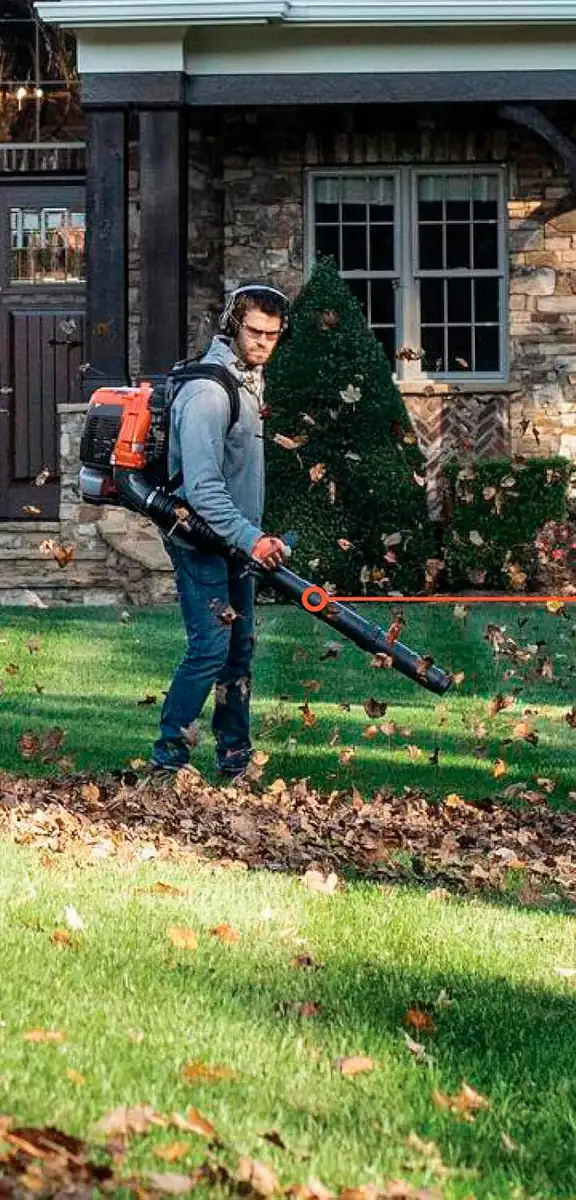 Man in ear protection and safety glasses clearing leaves from a lawn with a Husqvarna backpack blower