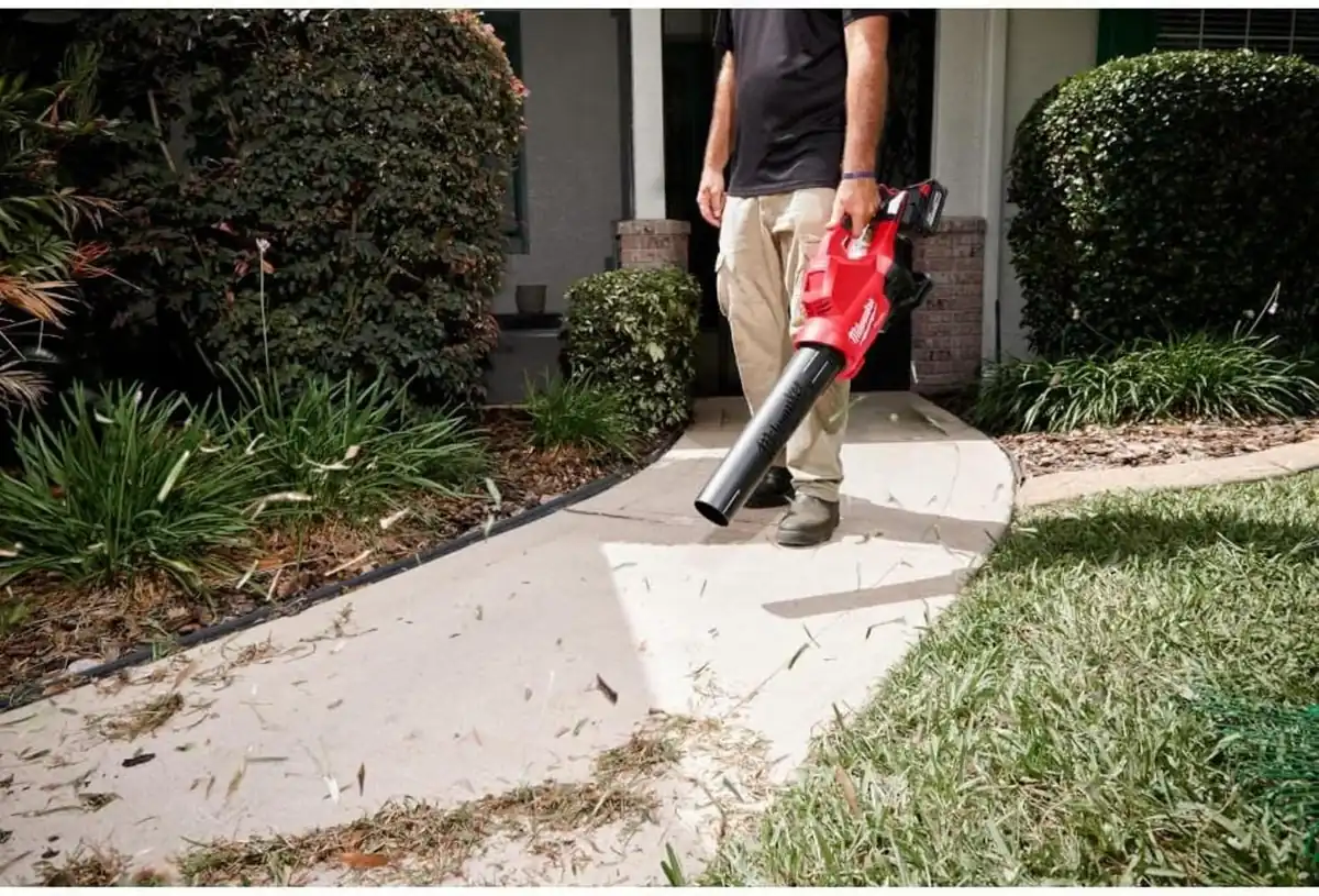 Man clearing grass clippings off a garden path with the Milwaukee M18 FUEL dual battery blower