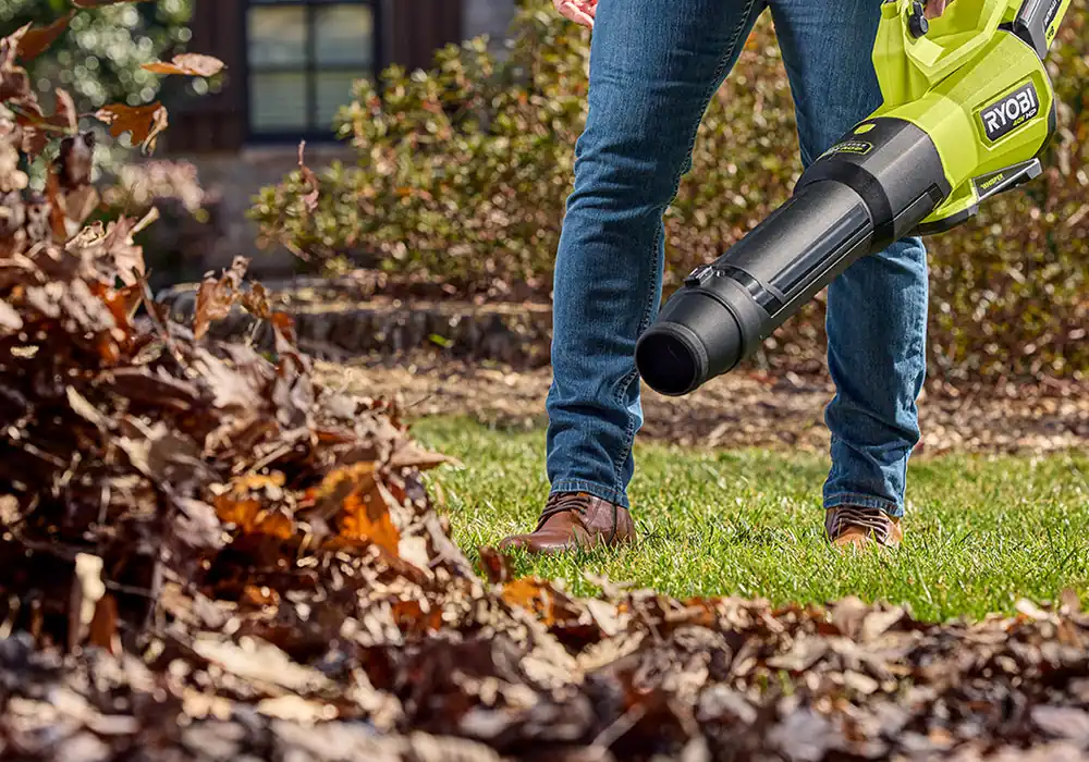RYOBI 40V HP 800 CFM blower with a battery fitted, clearing dry leaves off a lawn
