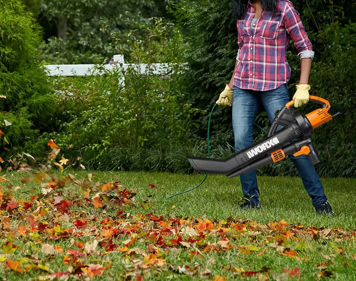WORX Trivac WG509 with its wide nozzle pointed at a lawn while leaves scatter ahead of it